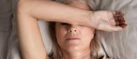 Close up top view middle-aged woman lying down in bed on pillow put hand on face, concept of female having insomnia sleeping disorder or migraine pain, melancholic mood, personal life troubles concept